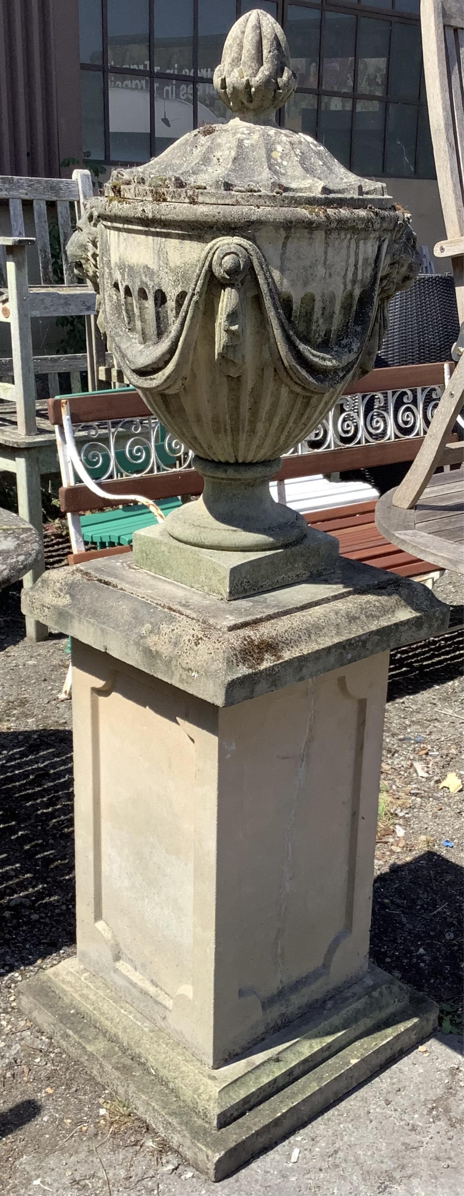 A reconstituted stone Adam style lidded garden urn on a square pedestal base, height 160cm